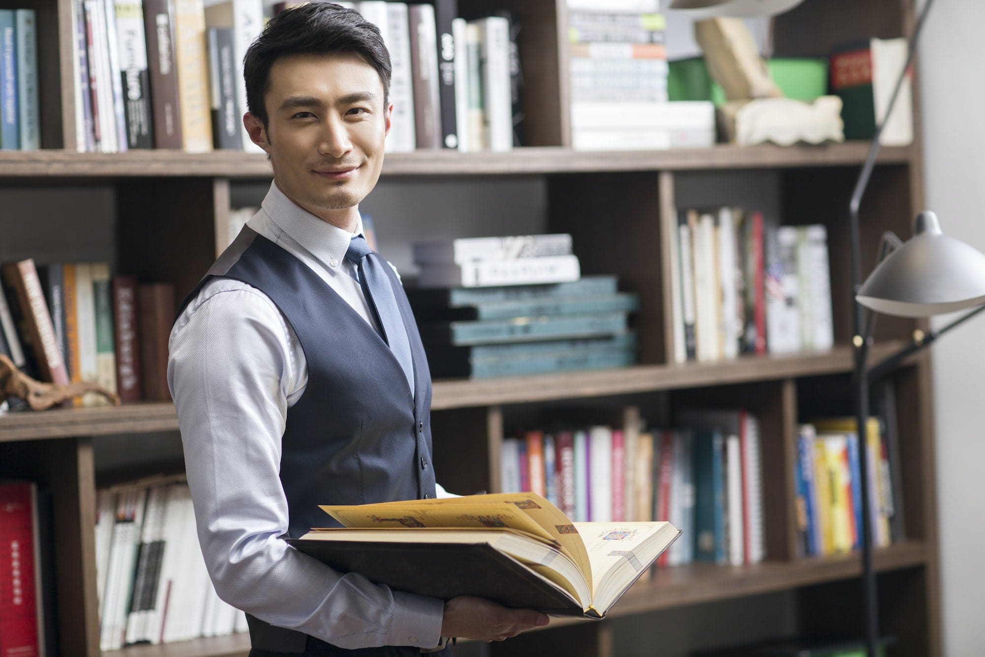 Young businessman reading book in his study